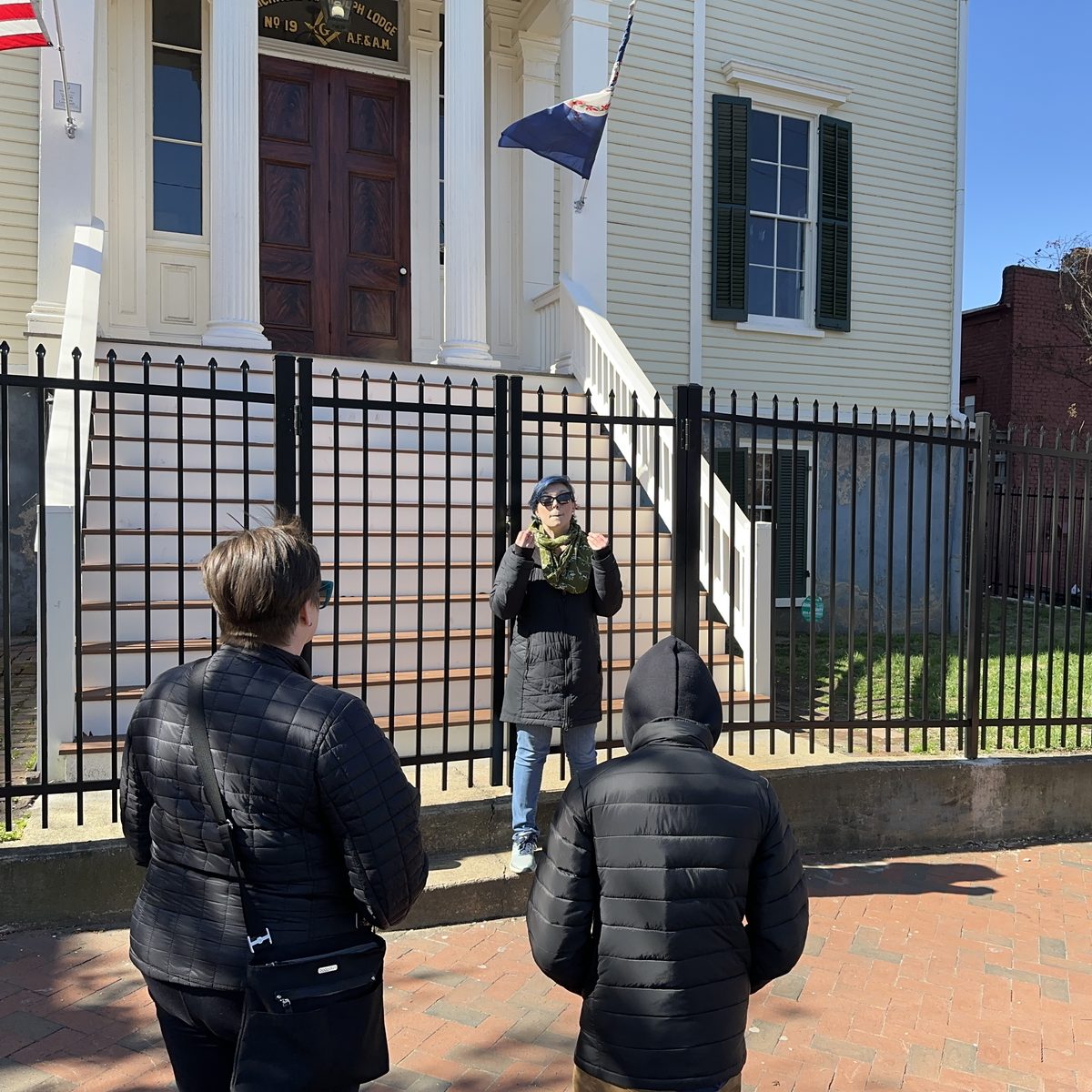 A storyteller speaking with guests outside a historic Church Hill building